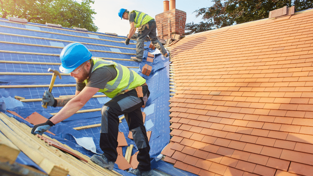 Two construction workers installing tiles during a professional roof replacement in Tampa.